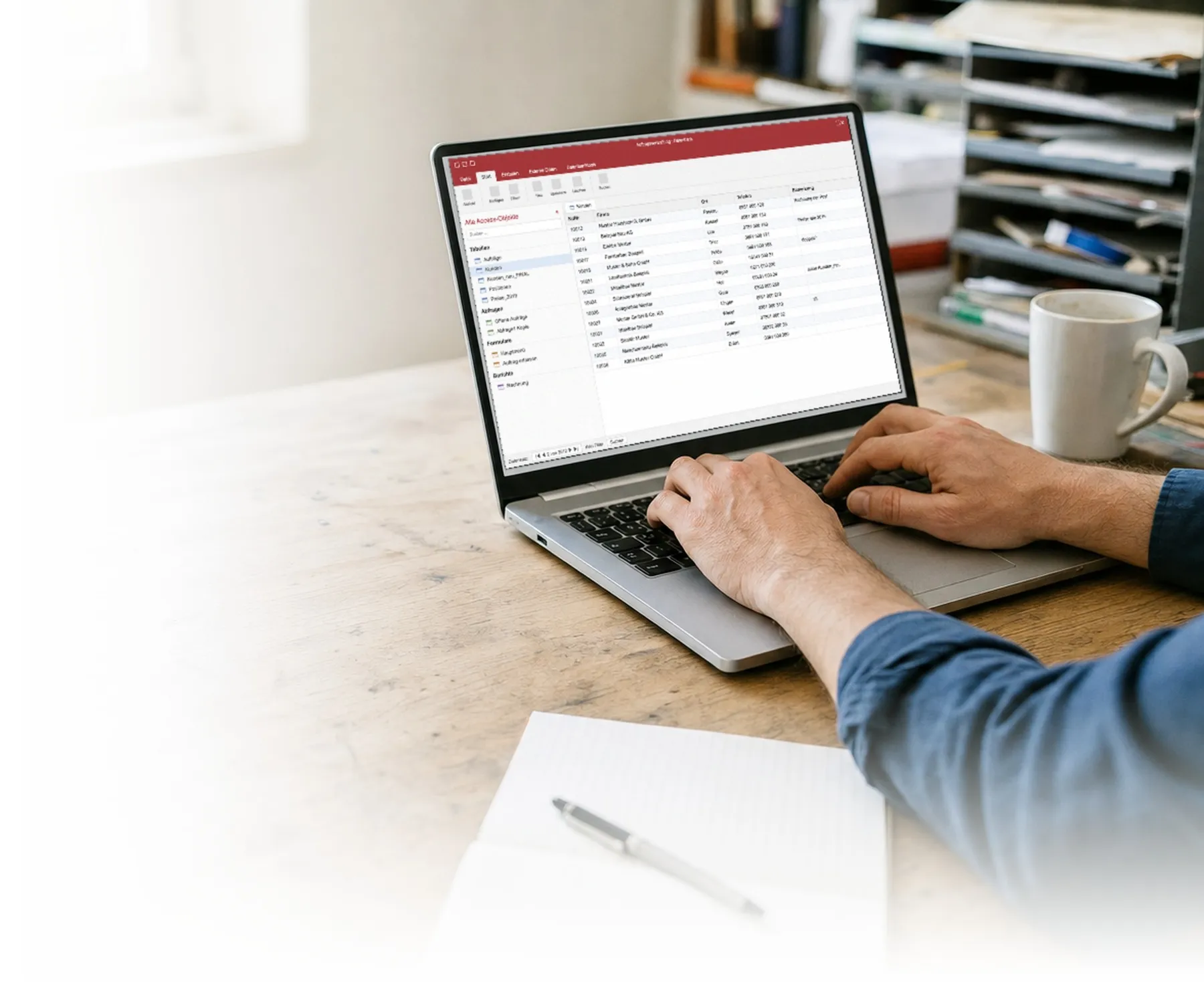 Hände an einem Laptop, auf dem Bildschirm eine Access-Datenbank mit einer Kundenliste